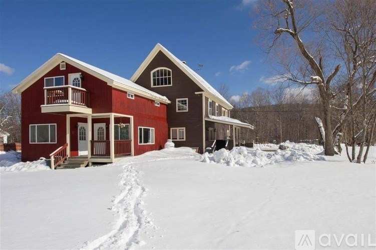 A red house with a balcony and a snow-covered ground.