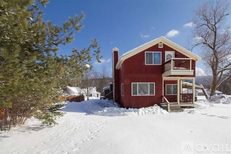 A red house with a balcony is surrounded by snow.
