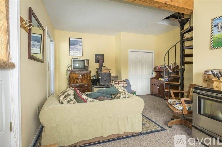 A bedroom with a bed, a television, a chair, and a staircase.