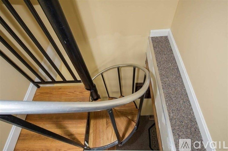 A spiral staircase with a metal railing and wooden steps.
