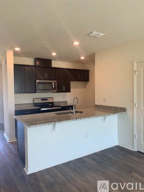 A kitchen with a granite countertop and black cabinets.