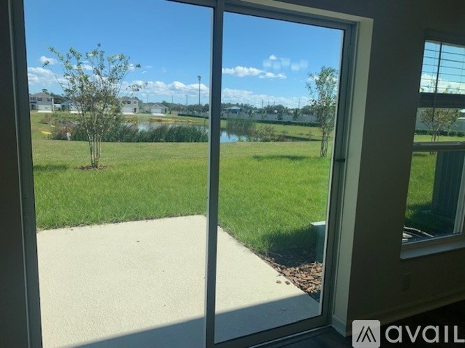 A view from inside a room looking out to a grassy area and a body of water.