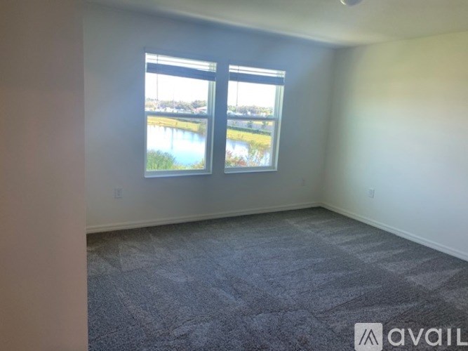 A room with a carpeted floor and a large window overlooking a body of water.