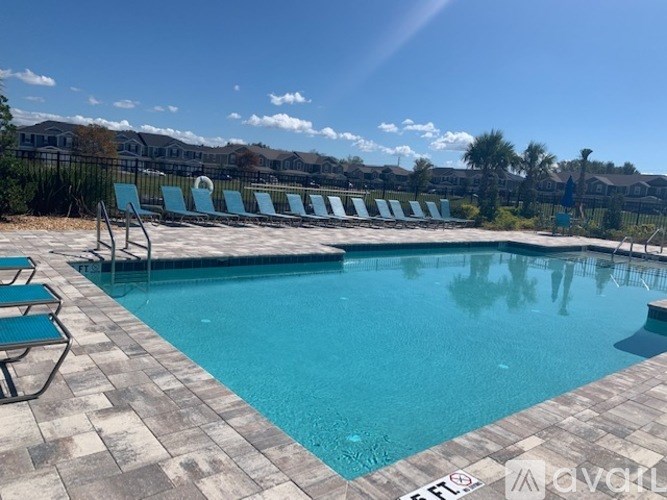 A swimming pool with lounge chairs and a clear blue sky.
