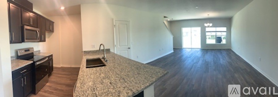 A spacious kitchen with granite countertops and dark wood flooring.