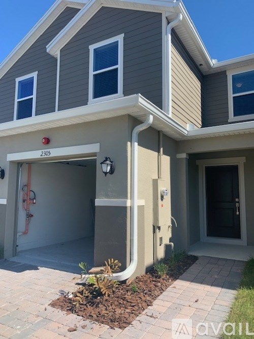 A grey house with a red fire hydrant in front of it.