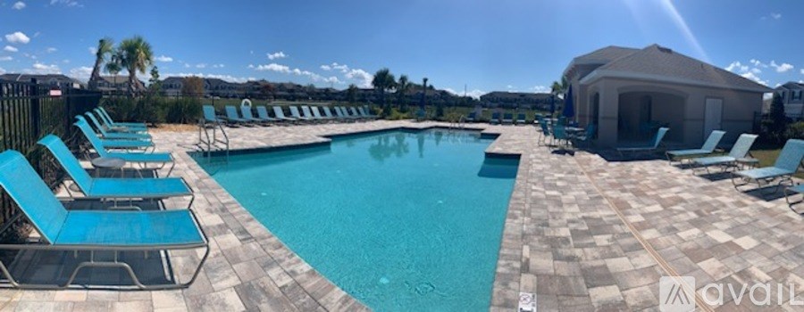 A pool surrounded by chairs and a building in the background.