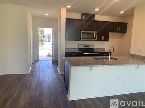 A kitchen with dark brown cabinets and a granite countertop is available.