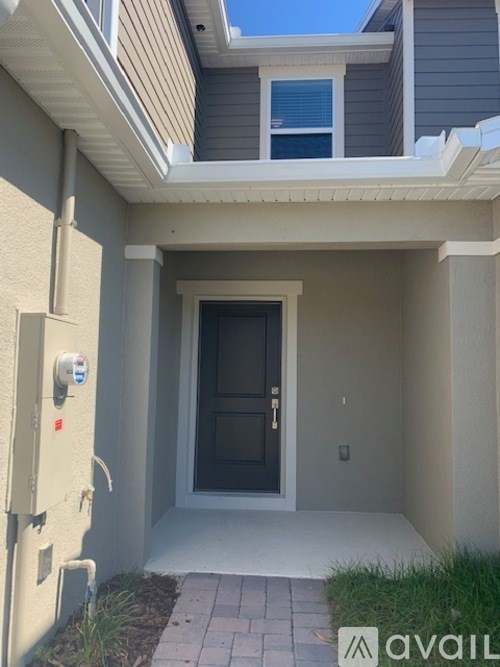 A modern house entrance with a black door and a security system.