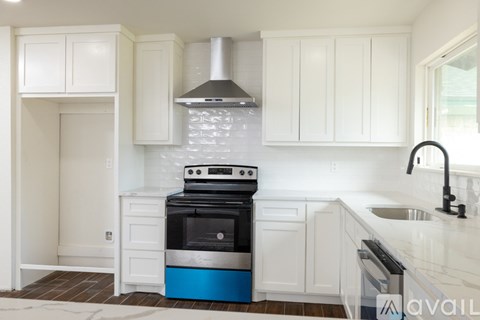 A kitchen with white cabinets and a blue stove.