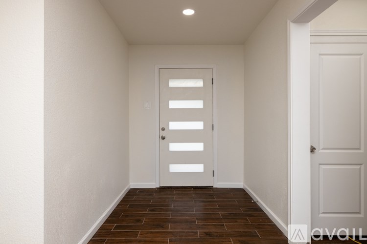 A white door with a window in the middle is in a room with a wooden floor.