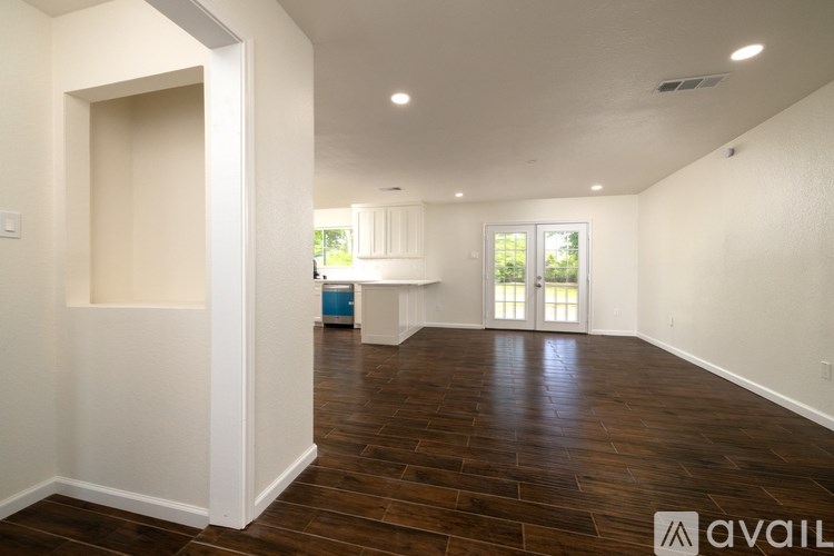 A spacious room with wooden flooring and white walls.