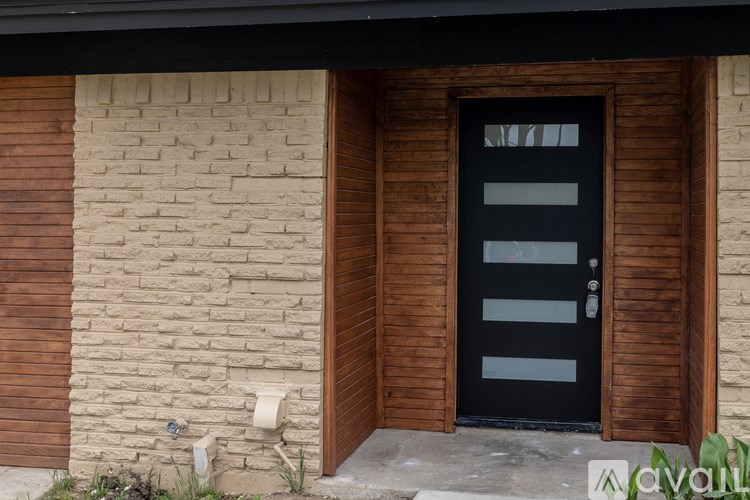 A black door with a glass panel is set in a wooden frame.
