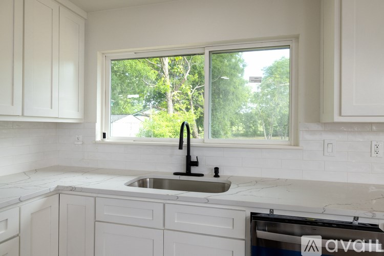 A kitchen with white cabinets and a marble countertop.