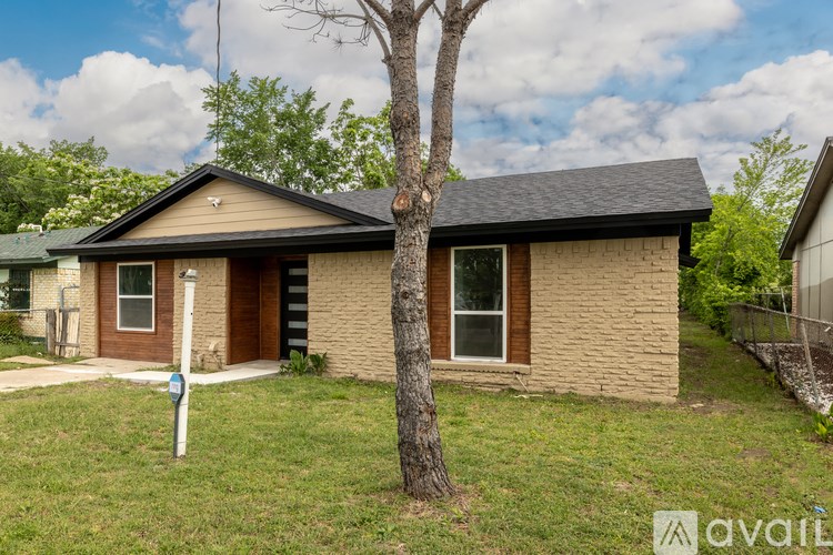 A house with a brown brick exterior and a black roof is for sale.
