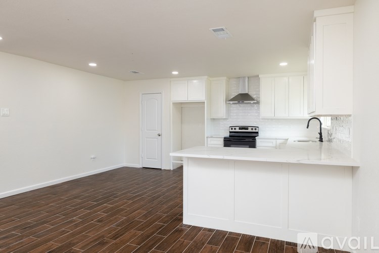 A kitchen with white cabinets and a wooden floor.