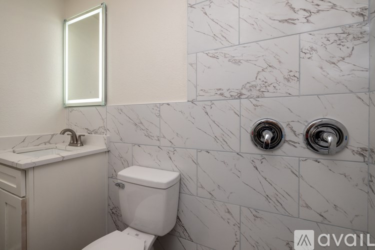 A bathroom with a toilet, sink, and marble tiles.