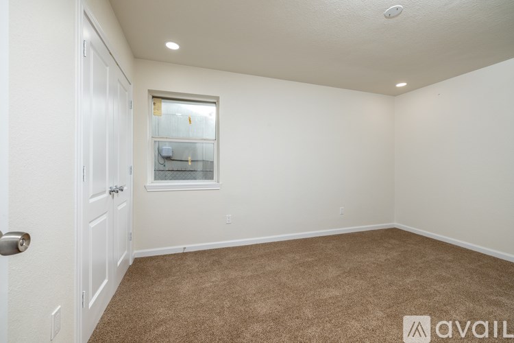 A room with a carpeted floor, a window, and a door.