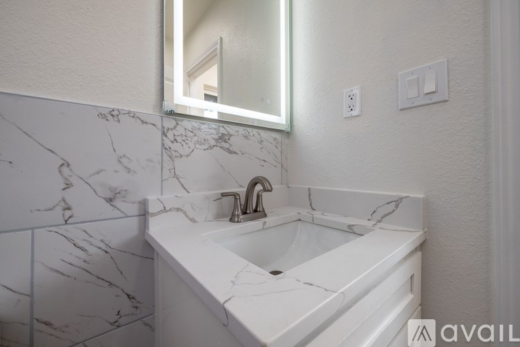 A bathroom sink with a marble countertop and a mirror above it.