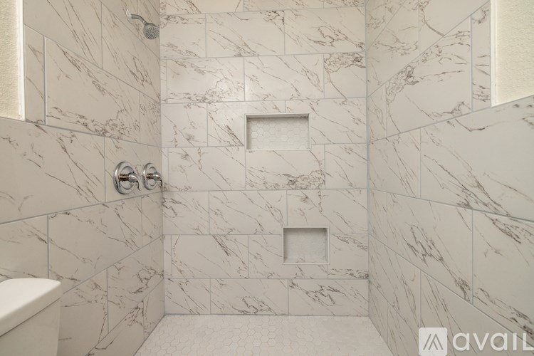 A bathroom with marble tiles and a white bathtub.