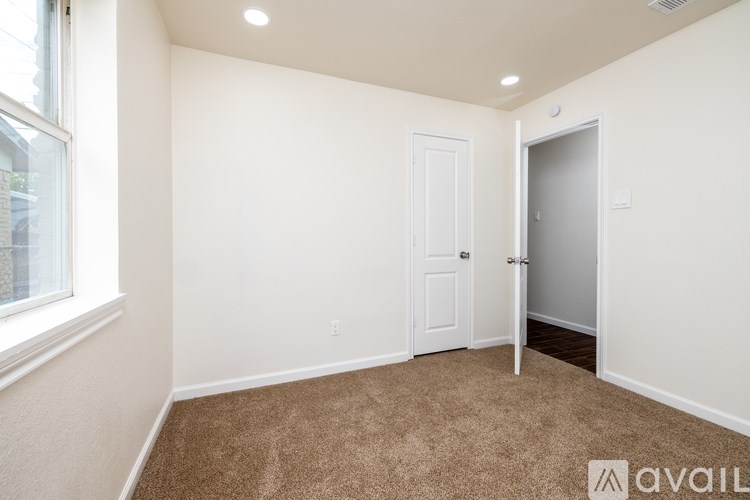 A room with a carpeted floor, a door, and a window.