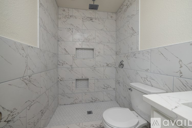 A bathroom with marble tiles and a white toilet.
