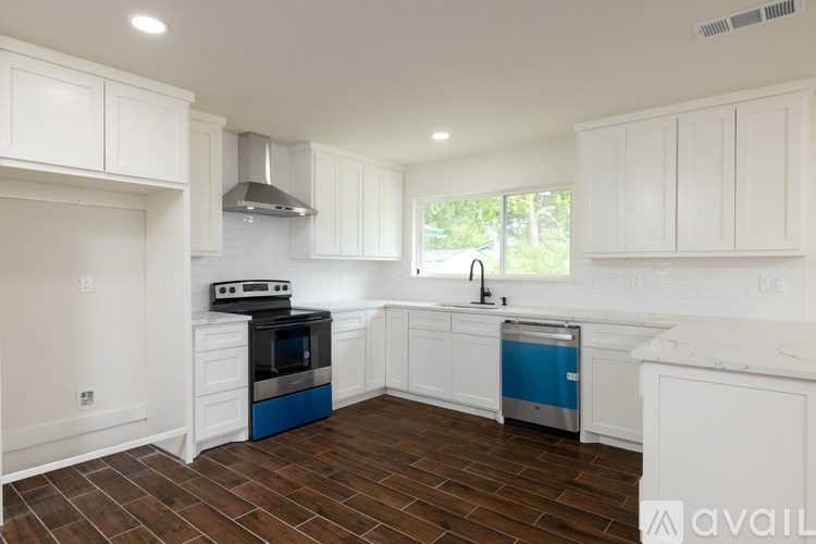 A kitchen with white cabinets and a blue dishwasher.