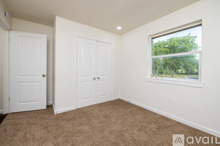 A room with two doors and a window with a view of trees outside.
