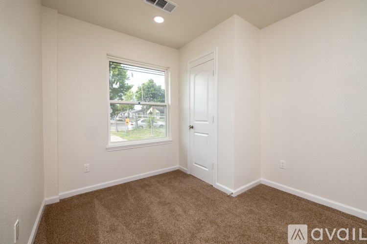 A room with a carpeted floor, a window, and a door.