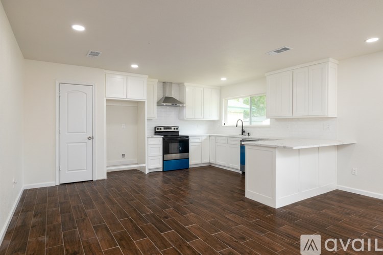 A kitchen with white cabinets and a wooden floor.