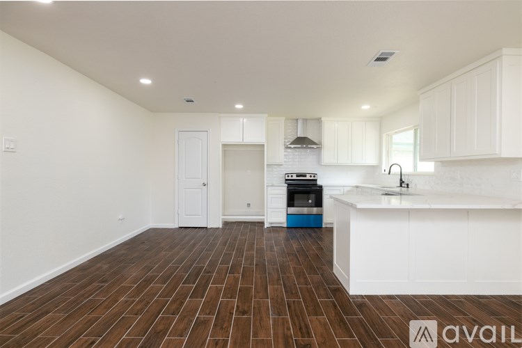 A kitchen with white cabinets and a wooden floor.