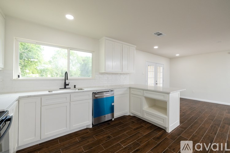 A kitchen with white cabinets and a blue dishwasher.