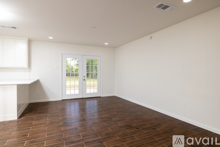 A room with wooden flooring and a sliding glass door.