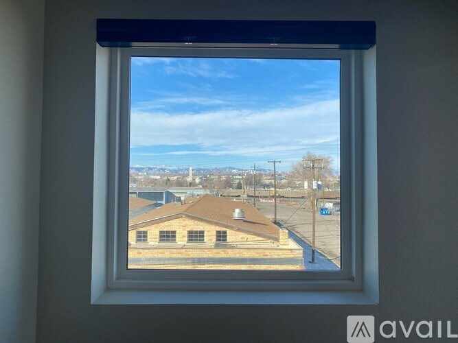 A window with a view of a building and a blue sky.