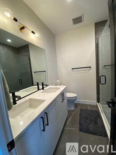 A bathroom with a sink, mirror, toilet and a rug.