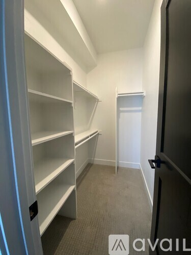 A white shelving unit in a room with a black door.