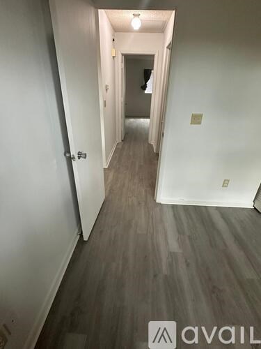 A long hallway with wood floors and white walls.