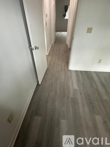 A hallway with a wooden floor and white walls.