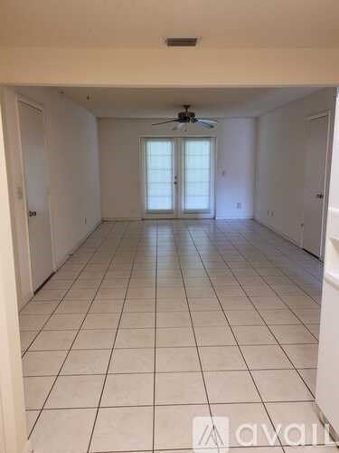 A spacious room with a ceiling fan and tiled flooring.