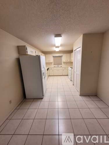 A kitchen area with a refrigerator and a sink.