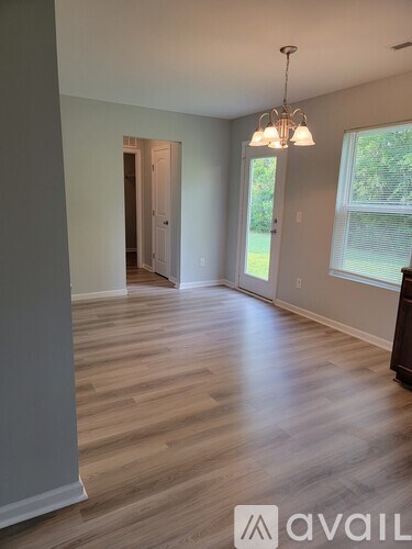 A room with wooden flooring and a chandelier hanging from the ceiling.
