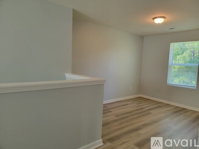 A room with wooden flooring and a window showing greenery outside.