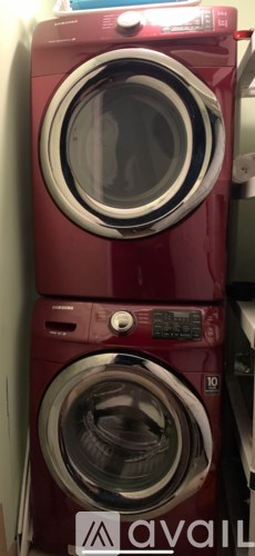 A red washing machine with a white door is stacked on top of another red washing machine.