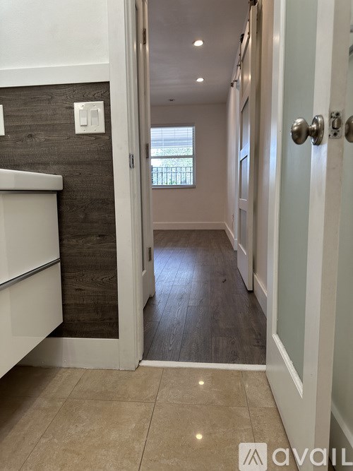 A hallway with a white door and a window in the background.