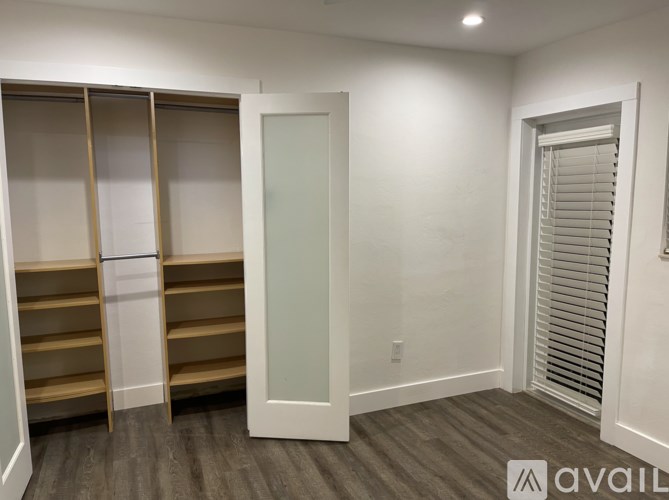 A room with a white door, a white wall, and a white closet with a sliding door.