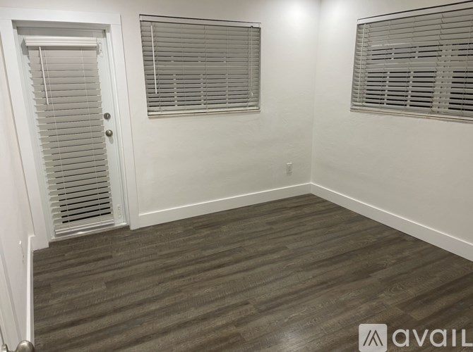 A room with a door and two windows with blinds.