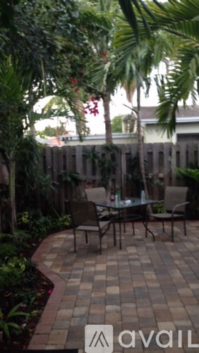 A patio with a table and chairs surrounded by greenery.