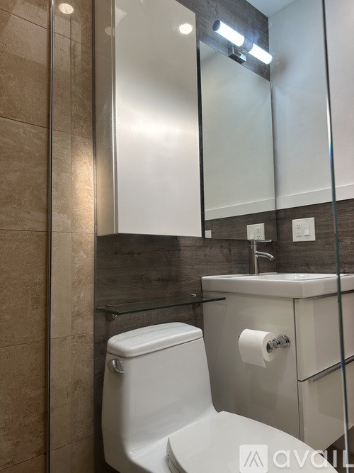 A white toilet with a roll of toilet paper on the side.