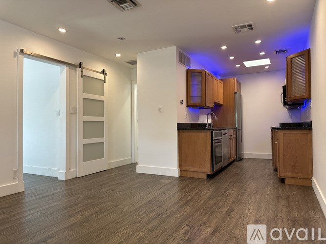 A kitchen with wooden cabinets and a black countertop is available for rent.
