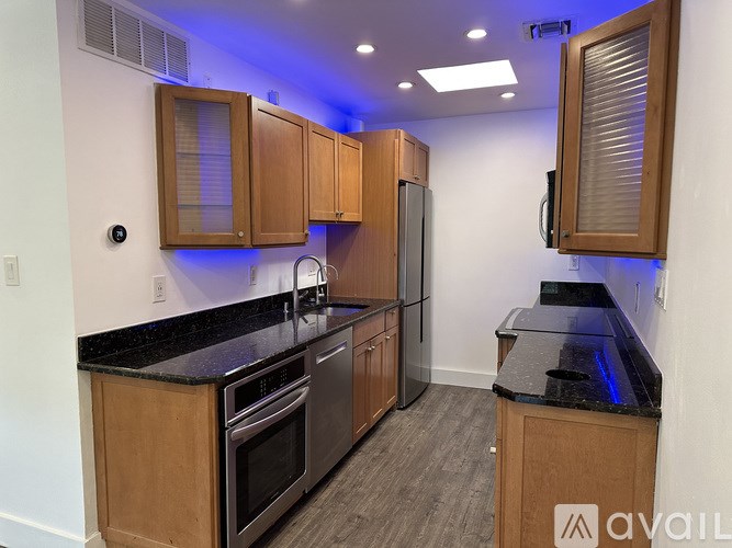 A kitchen with wooden cabinets and black countertops.
